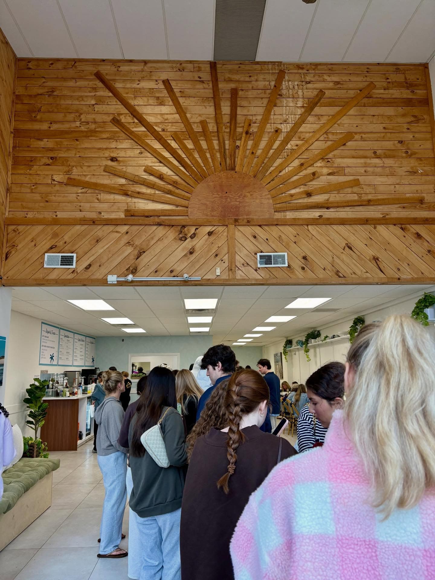 A full house at La Costa — the queue to the counter under the shop's wooden sunburst wall